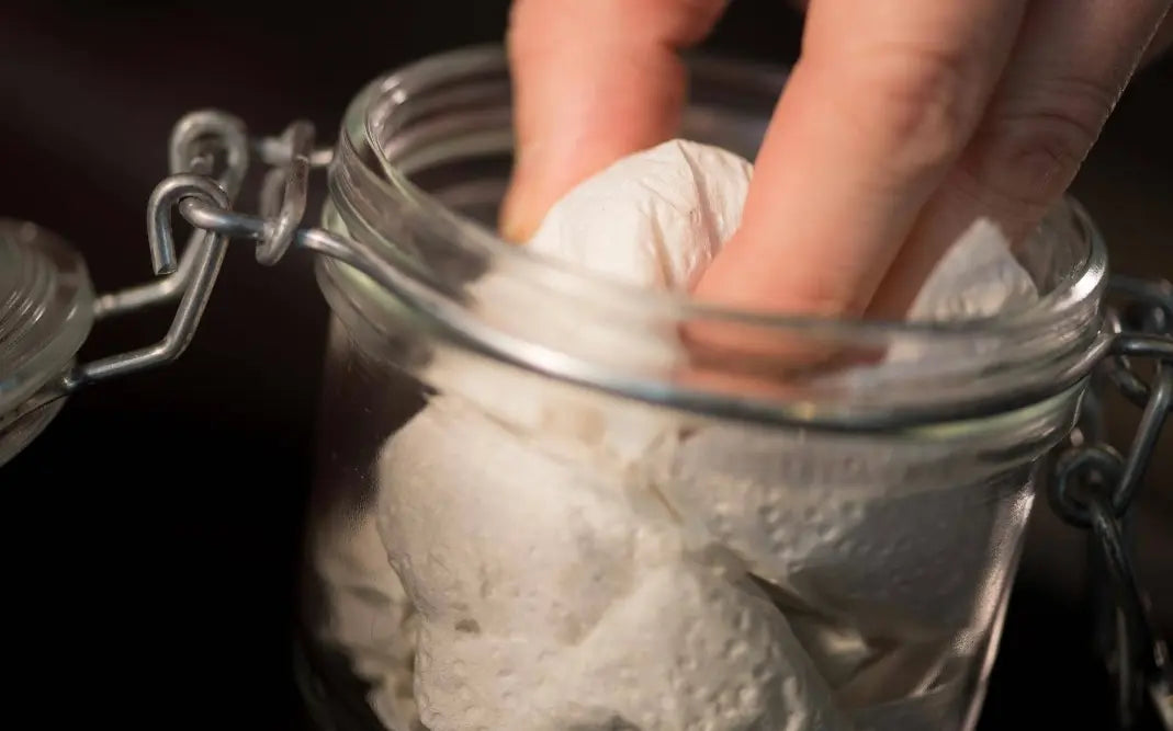 Fresh truffle wrapped in paper towel being placed in an airtight glass jar for proper storage