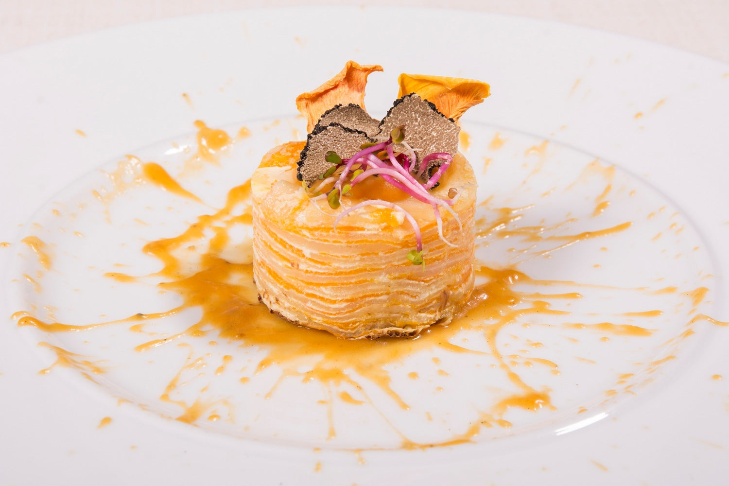 Potato millefoglie layered with truffle pumpkin cream and garnished with summer truffle slices