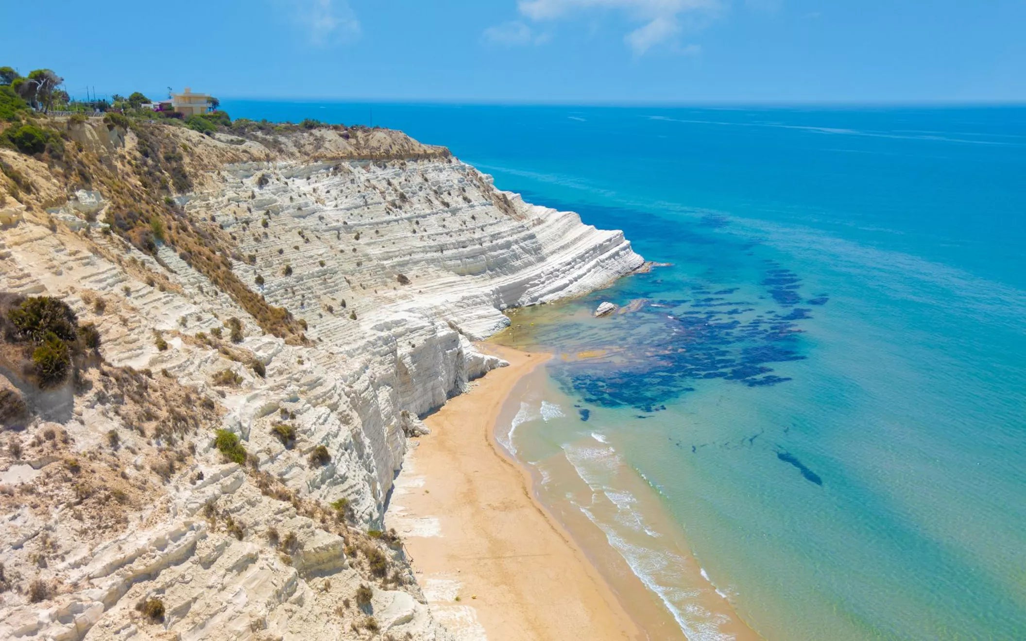 textAerial view of white limestone cliffs meeting the turquoise Mediterranean Sea along the southern coast of Sicily