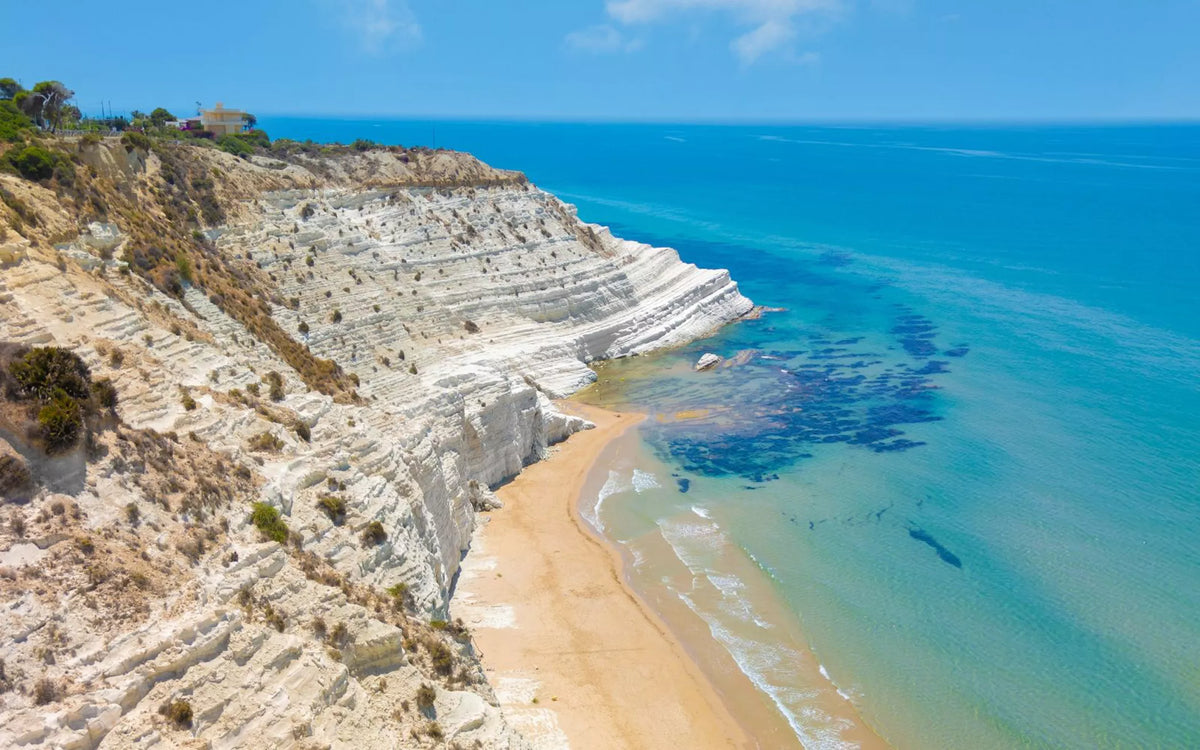  textAerial view of white limestone cliffs meeting the turquoise Mediterranean Sea along the southern coast of Sicily