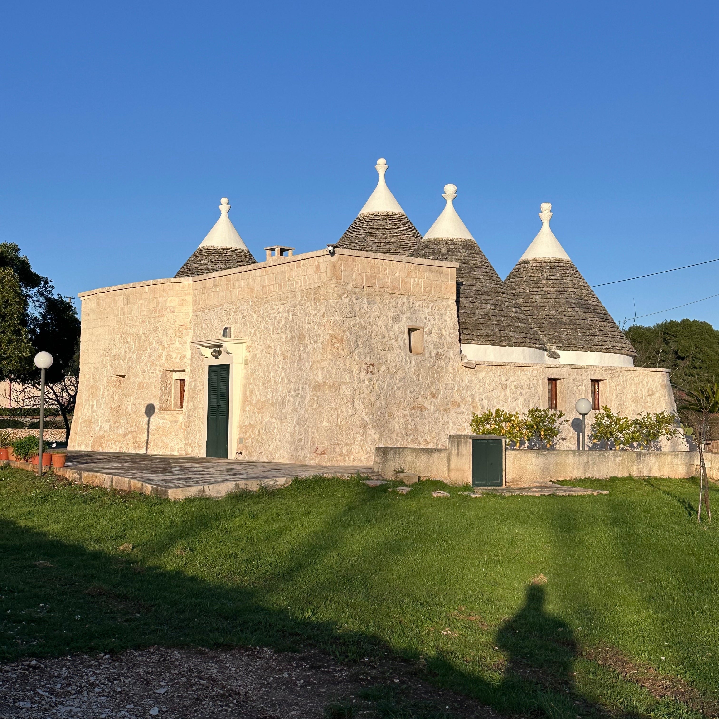 Traditional stone trulli in the Puglian countryside beneath a clear blue sky.