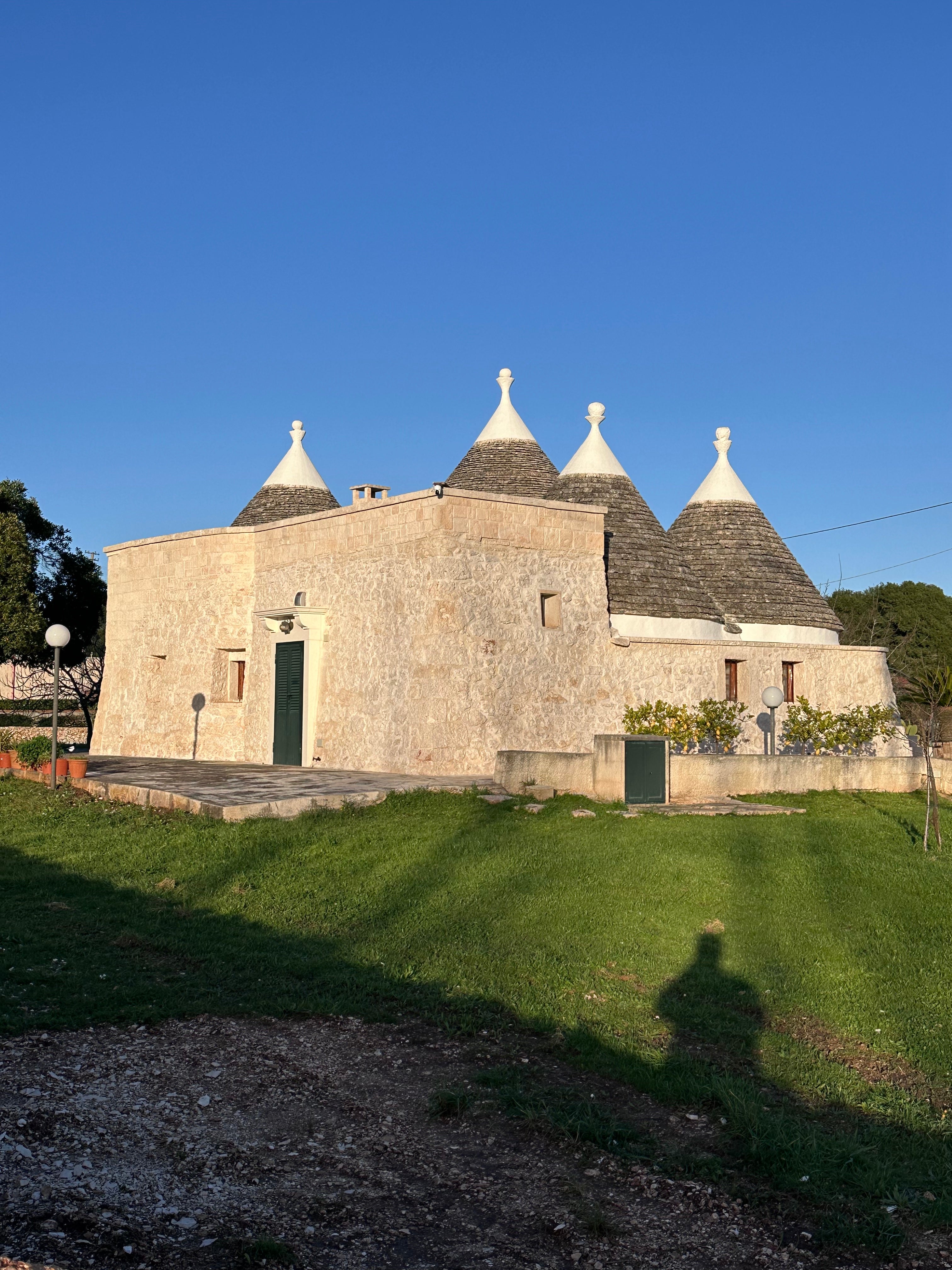 Traditional stone trulli in the Puglian countryside beneath a clear blue sky.