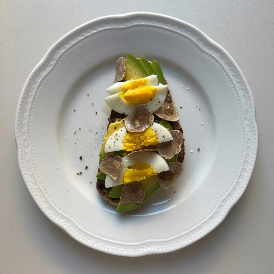 Fresh avocado toast topped with shaved white truffle Tuber Magnatum Pico on wholegrain bread