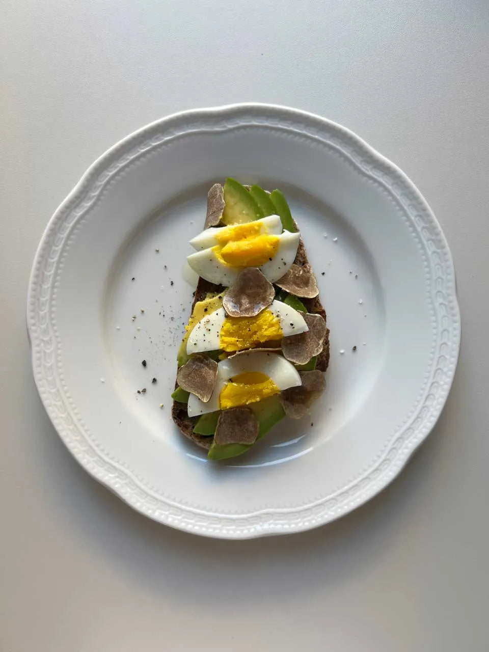Fresh avocado toast topped with shaved white truffle Tuber Magnatum Pico on wholegrain bread
