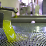Fresh cloudy olive oil flowing from mill equipment after mechanical extraction